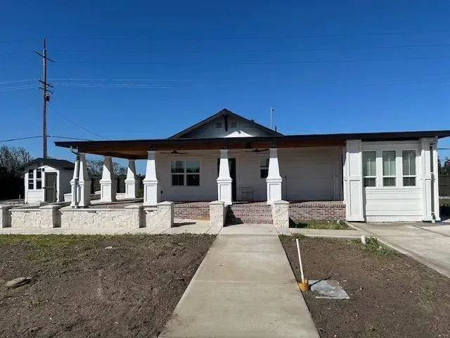 A white house with a porch and a walkway leading to it.