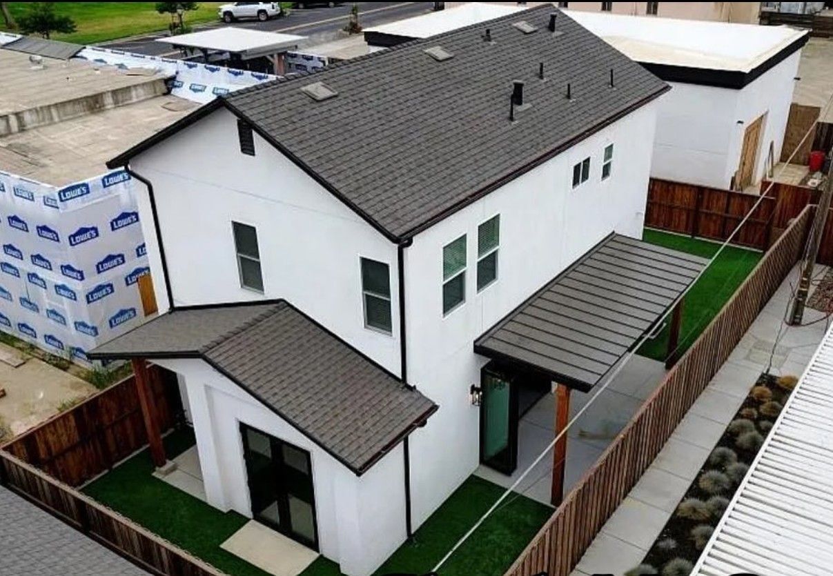 An aerial view of a white house with a brown roof