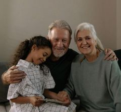 A man and two women are sitting on a couch with a little girl.