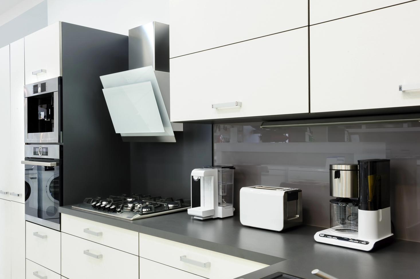 Cocina moderna con gabinetes blancos, encimera gris, electrodomésticos: horno, estufa, tostadora, cafetera.