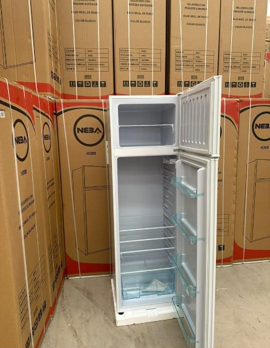 Refrigerador blanco con la puerta abierta, rodeado de cajas de cartón apiladas.