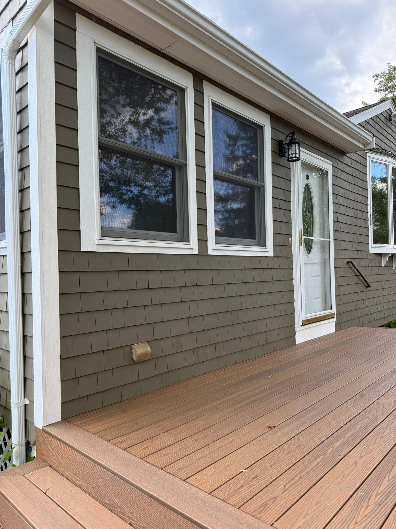 House exterior with white-trimmed windows, tan siding, and a wooden deck in front
