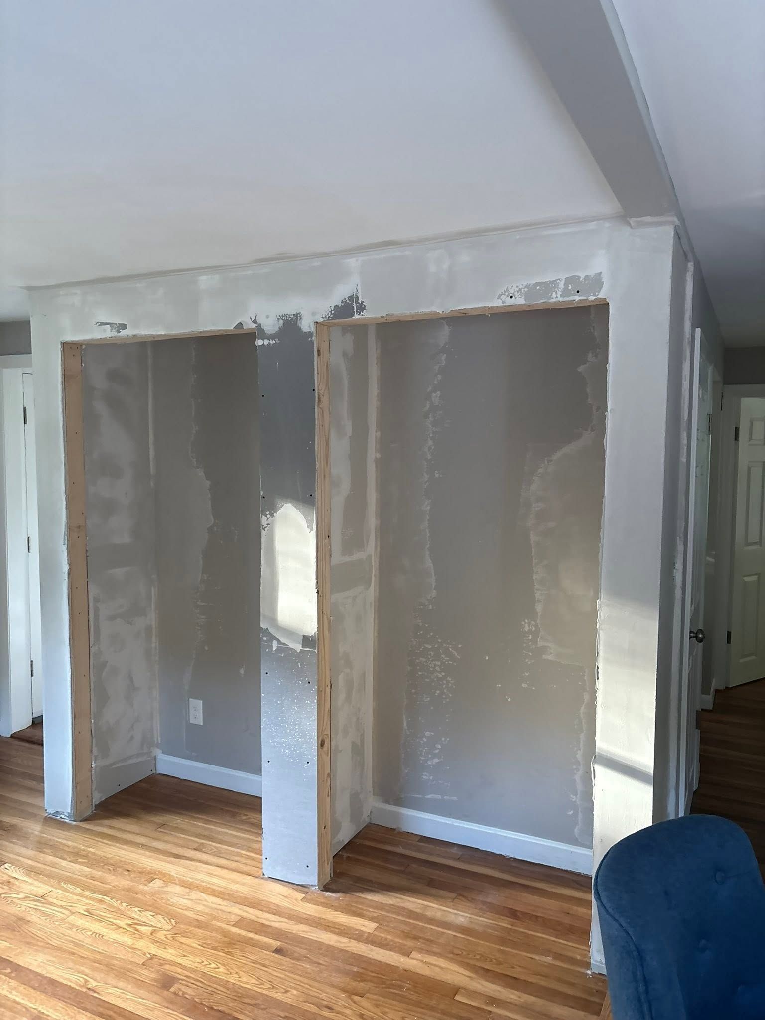 Unfinished drywall closet framing in a room with hardwood floors and white walls