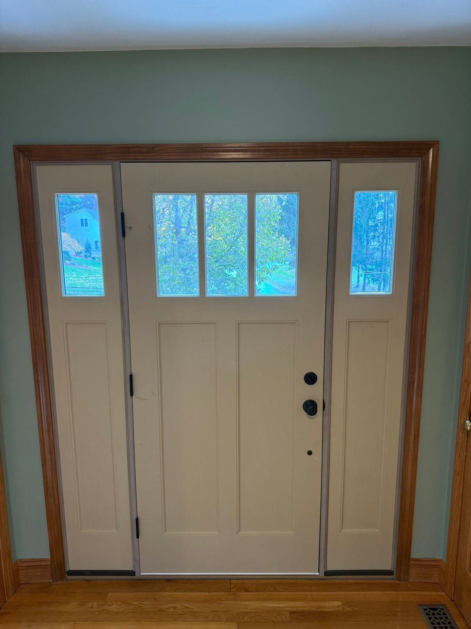White front door with sidelights and a wood frame inside a home entryway.
