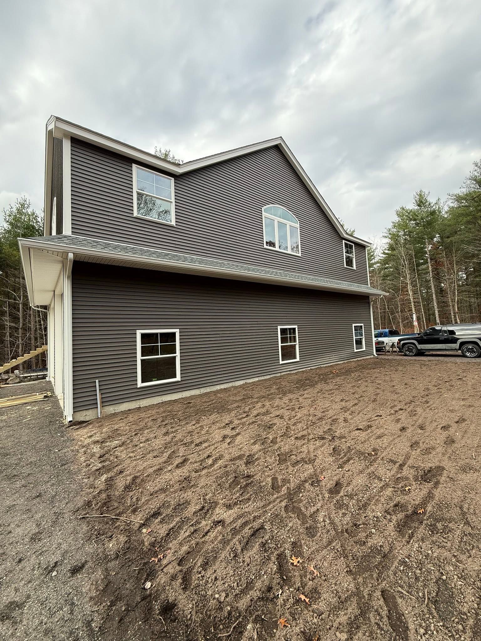 Modern dark-gray house with wavy siding and a steep roof on a mulched lot