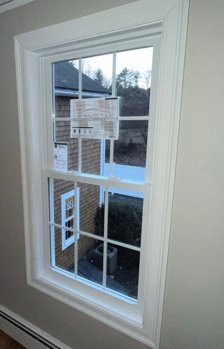 White-trimmed window overlooking snowy outdoors, with a building visible outside.