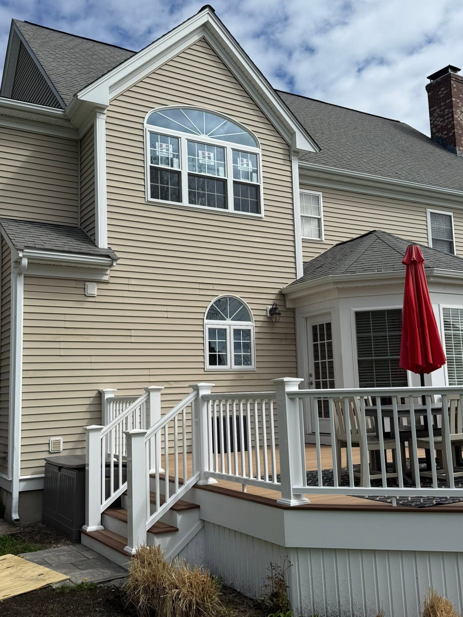 Back deck and beige townhouse exterior with white railings and red patio umbrella