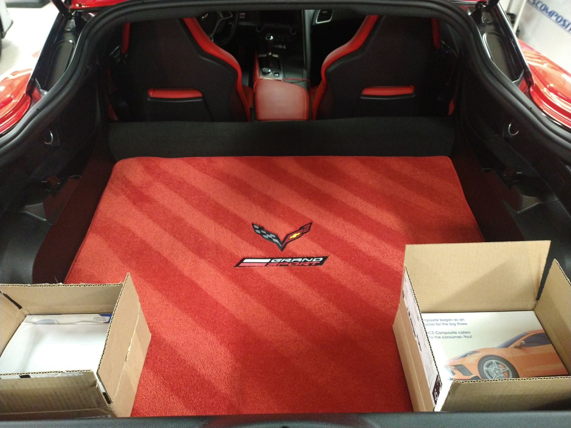 The trunk of a corvette with a red rug and boxes