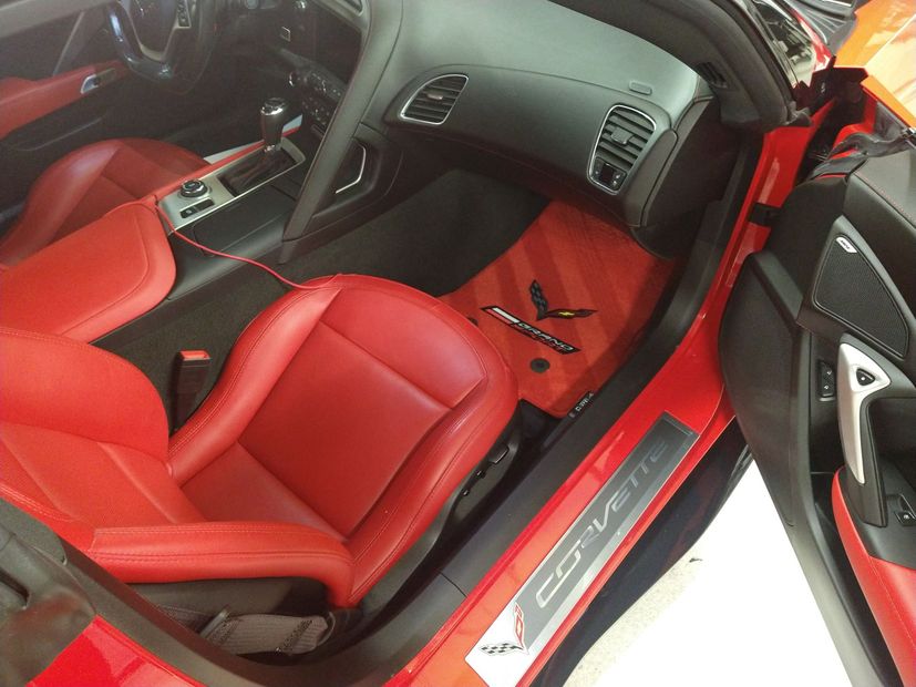The inside of a red corvette with the door open