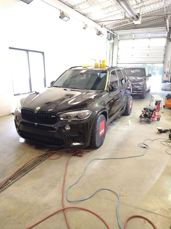 A black car is parked in a garage with other cars.