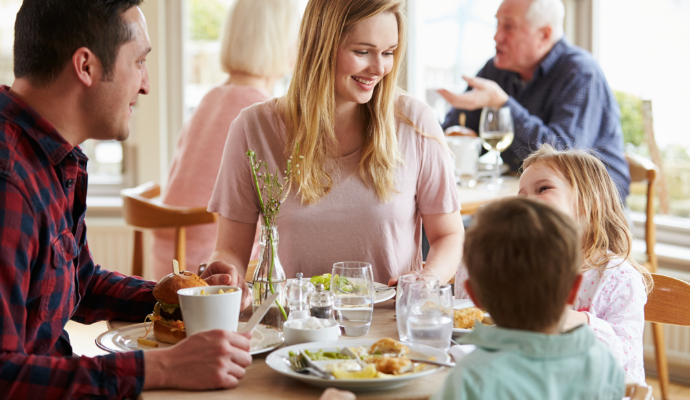 Uma família está sentada à mesa de um restaurante comendo.