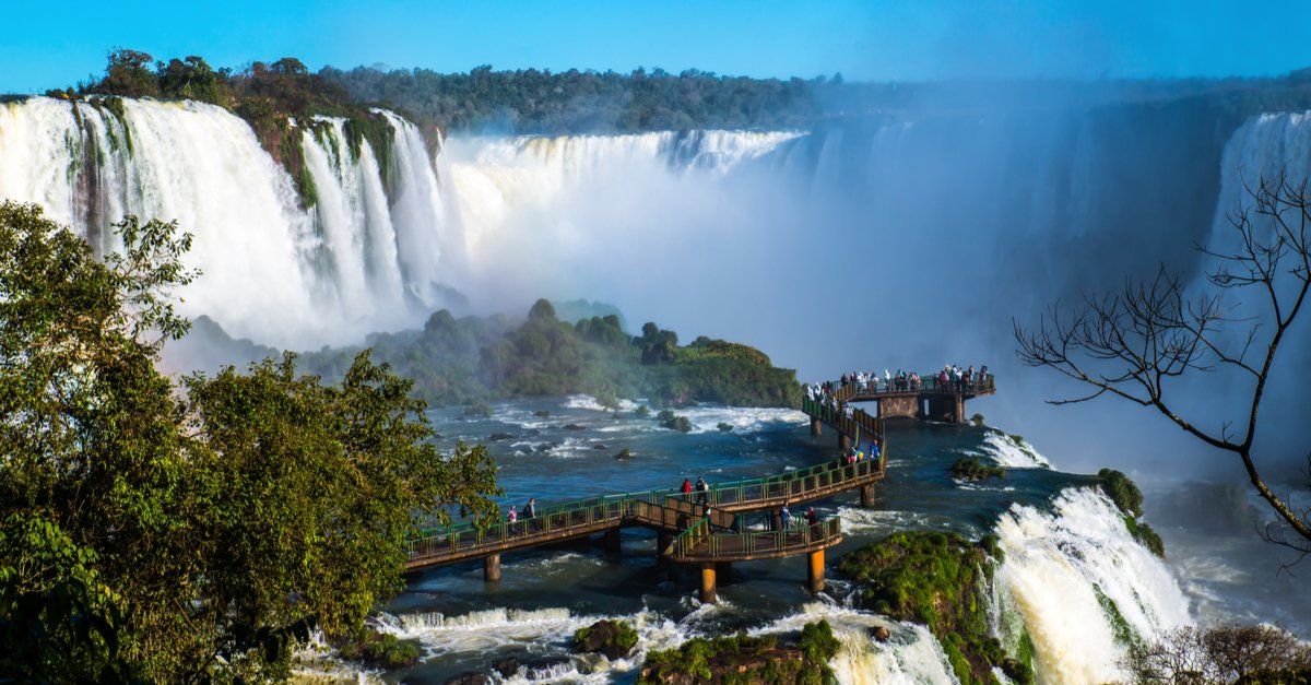 Passarela sobre as águas das Cataratas do Iguaçu, com pessoas apreciando o cenário