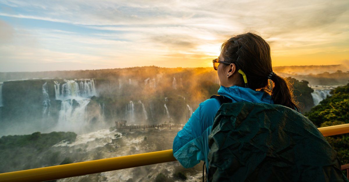 Mulher apreciando o pôr do sol com as Cataratas do Iguaçu ao fundo