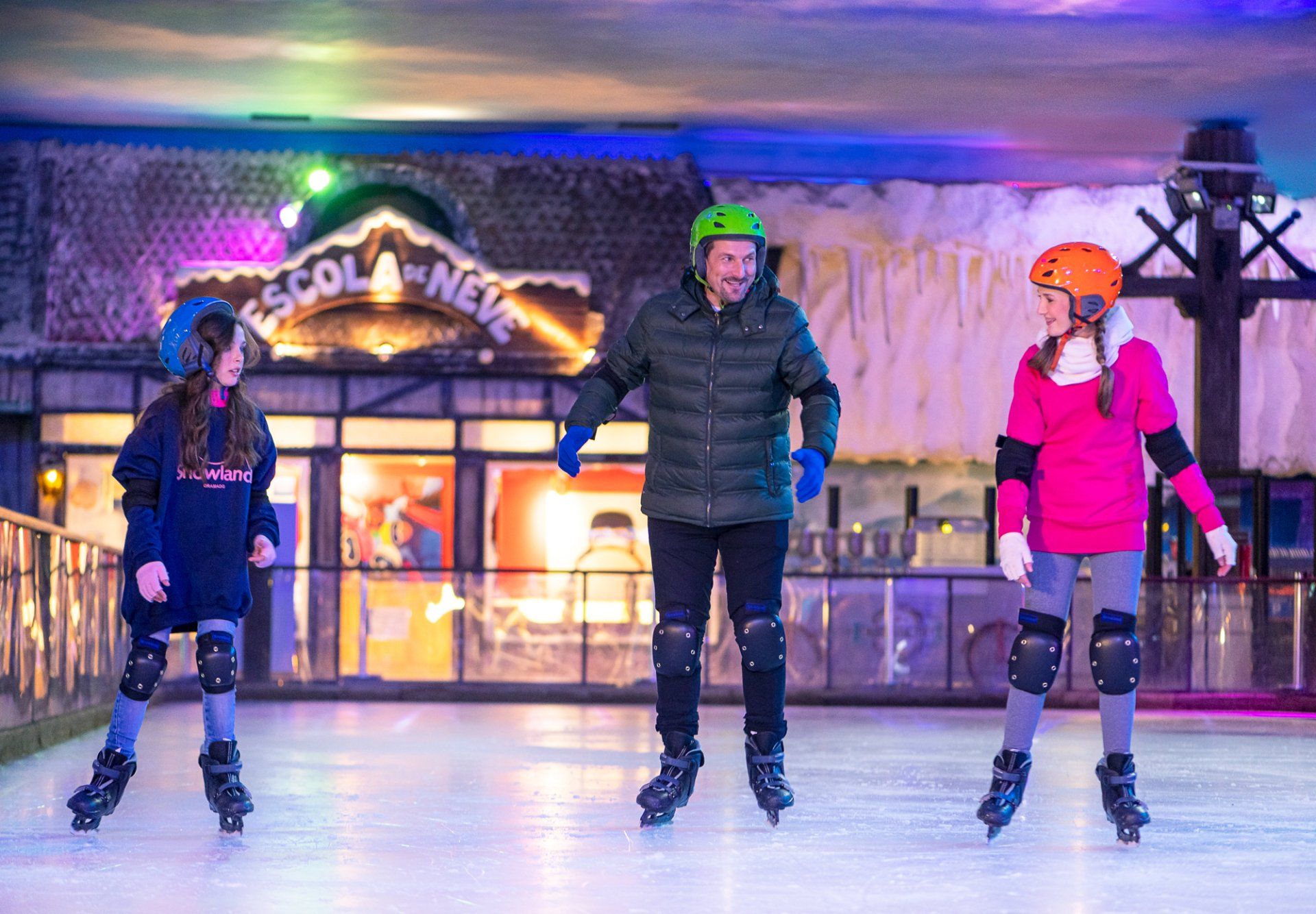Pai patinando com as filhas na pista de patinação do Snowland