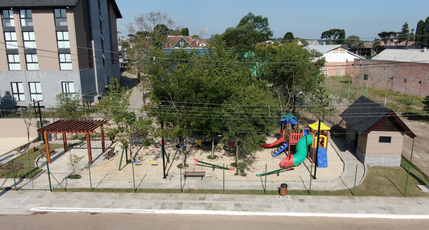 Vista aérea da praça pública construída pela Gramado Parks, com brinquedos coloridos e quadra de areia