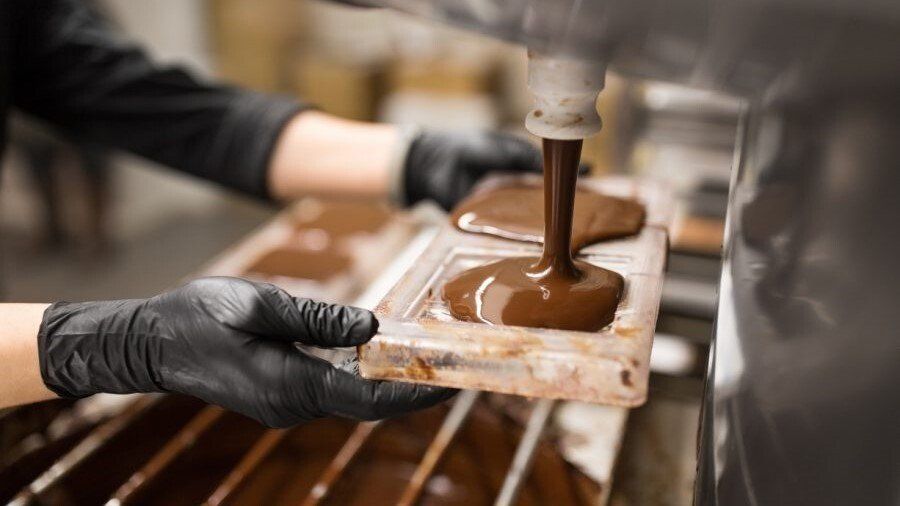 Chocolate derretido sendo colocado nas formas através do processo de produção artesanal de chocolate em Gramado