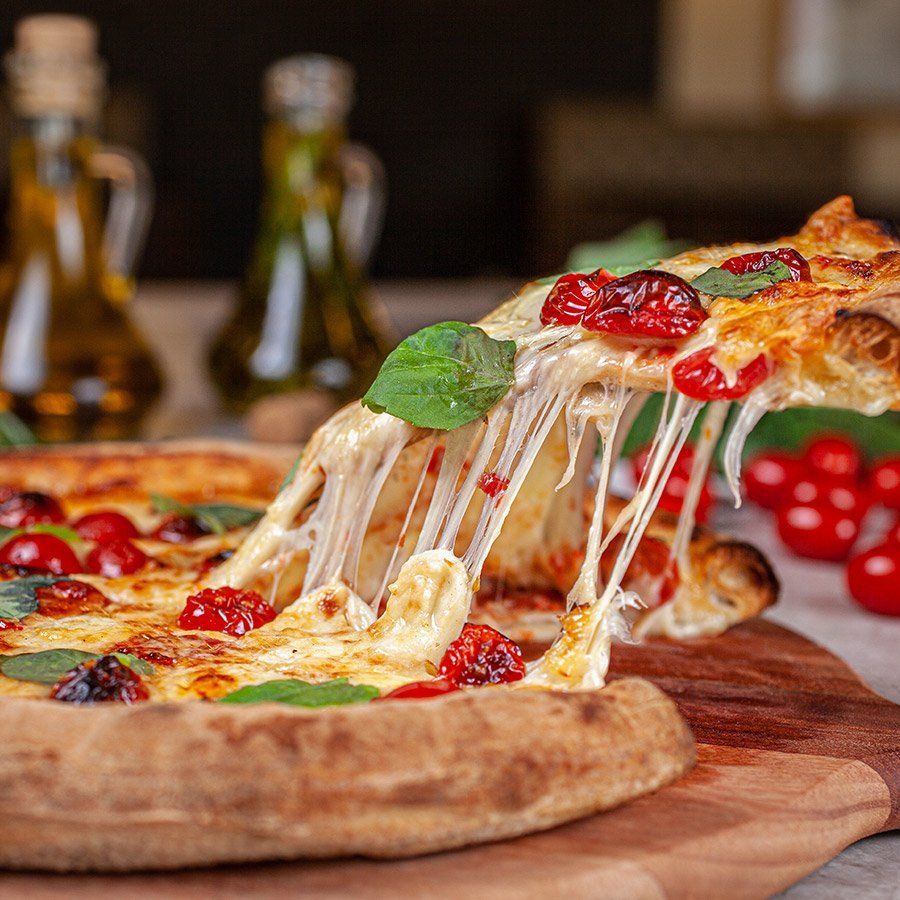 Uma pizza com queijo saindo dela está sobre uma tábua de madeira.