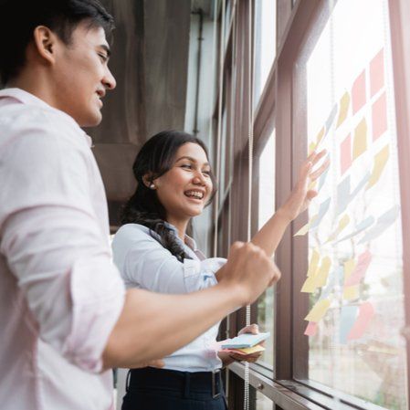 Um homem e uma mulher estão olhando pela janela para post-its.