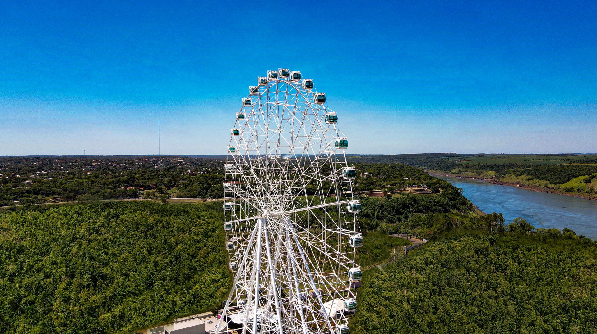 Uma vista aérea de uma roda gigante cercada por árvores e um rio.