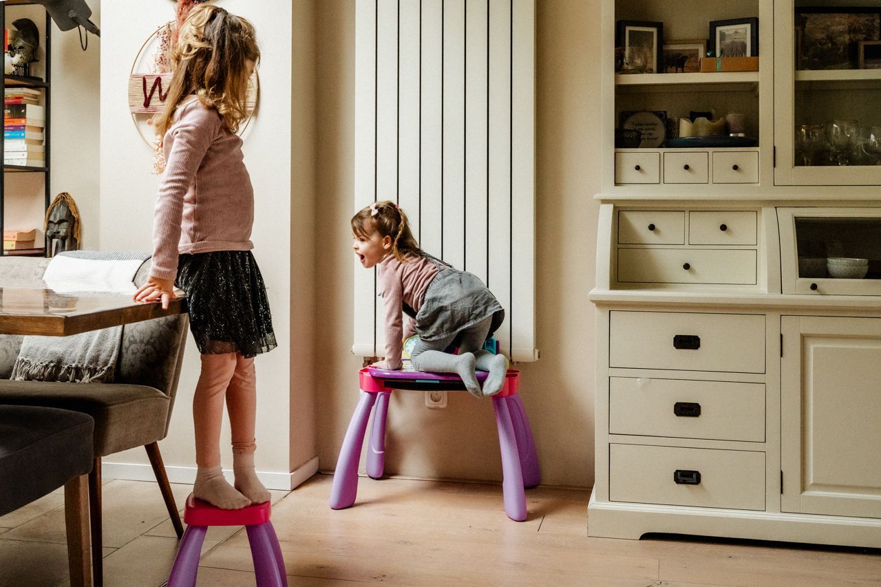 Twee kleine meisjes spelen in een woonkamer.
