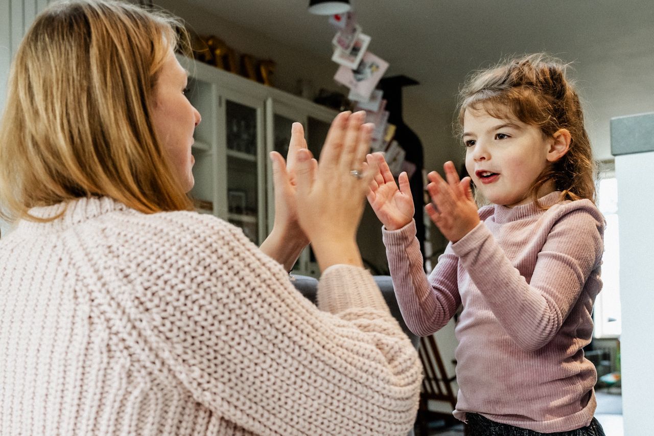 Een vrouw en een klein meisje geven elkaar een high five.