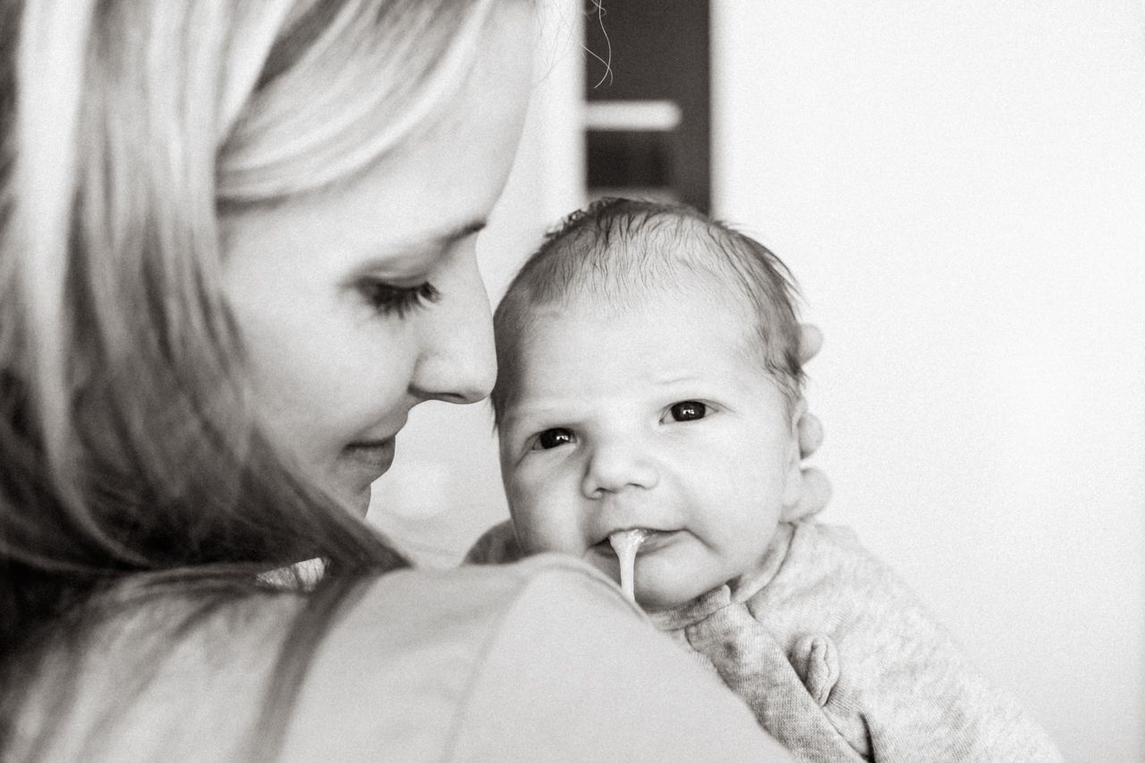 Een vrouw houdt een baby vast met spuug uit de mond.