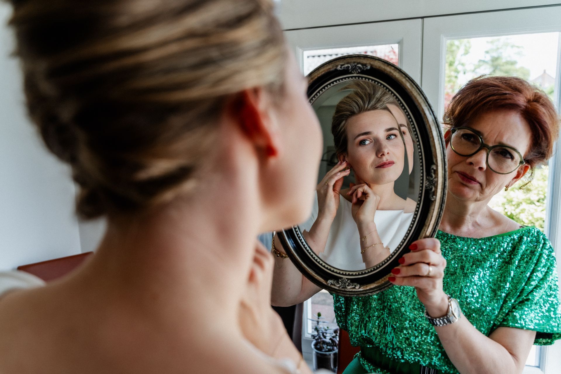 Een vrouw in een groene jurk kijkt naar haar spiegelbeeld in een spiegel.