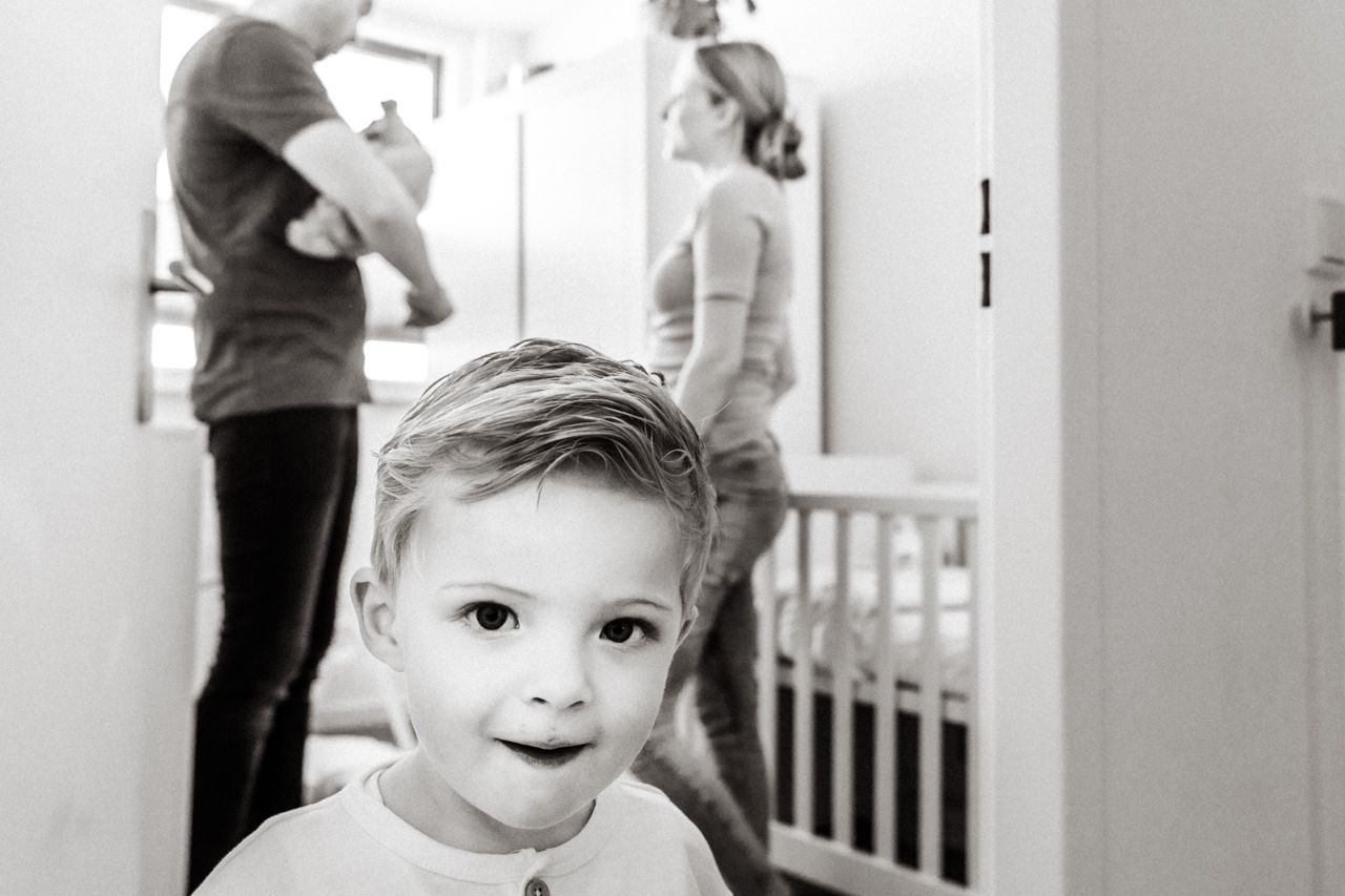 Op een zwart-witfoto zit een jongetje voor een wiegje.