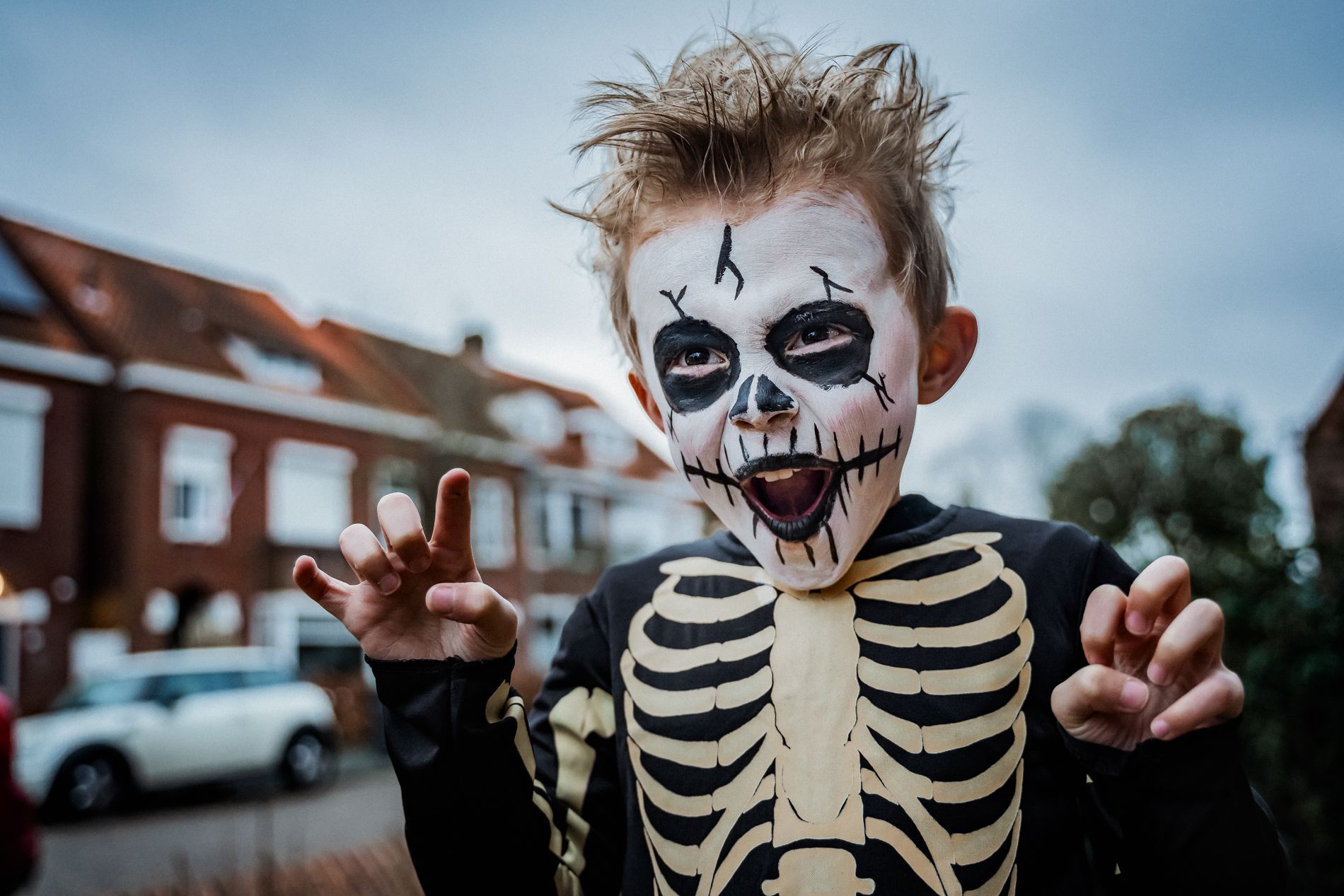 Een jonge jongen is gekleed in een skeletkostuum voor Halloween.