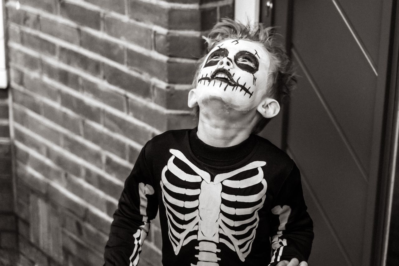 Een zwart-witfoto van een jonge jongen verkleed als skelet.