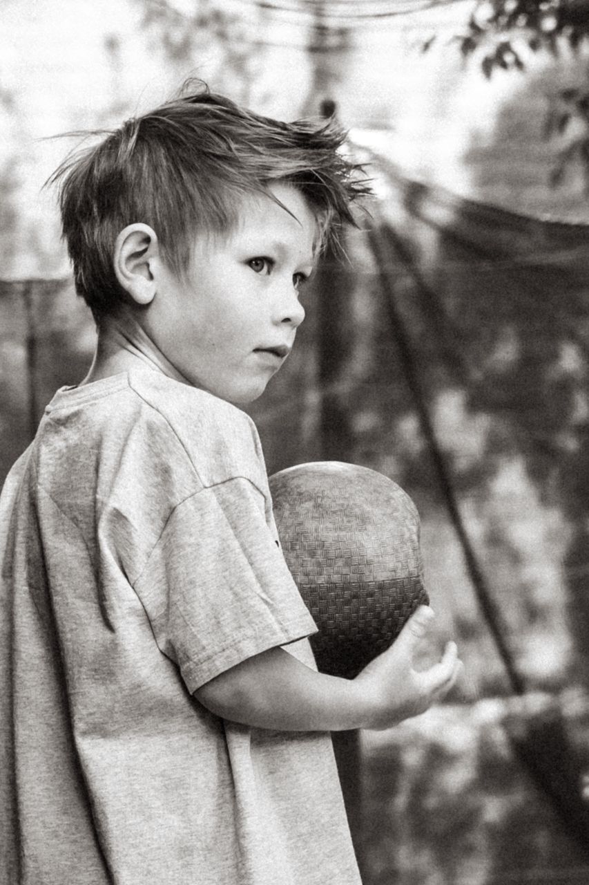 Een jonge jongen houdt een bal in zijn handen op een zwart-witfoto.