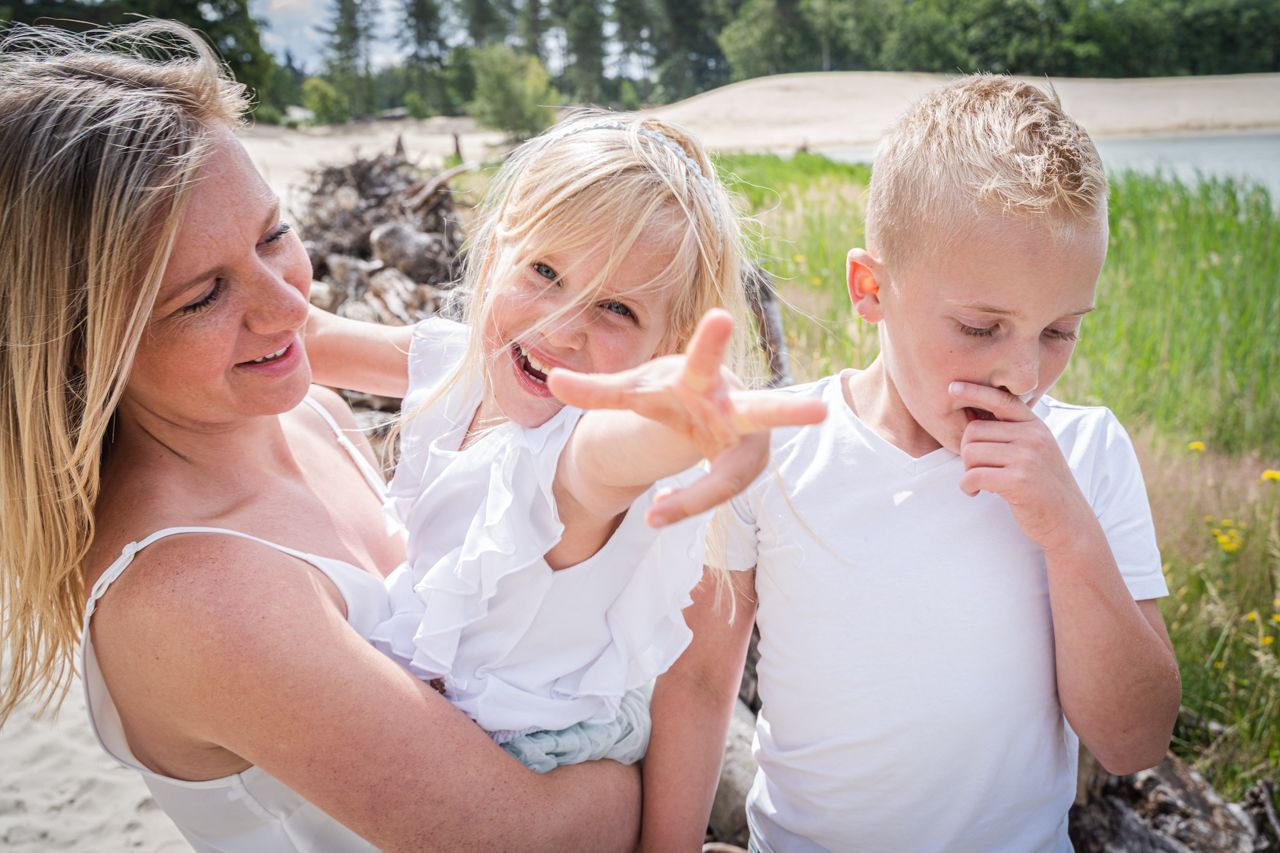 Een vrouw houdt twee kinderen vast en wijst naar iets.