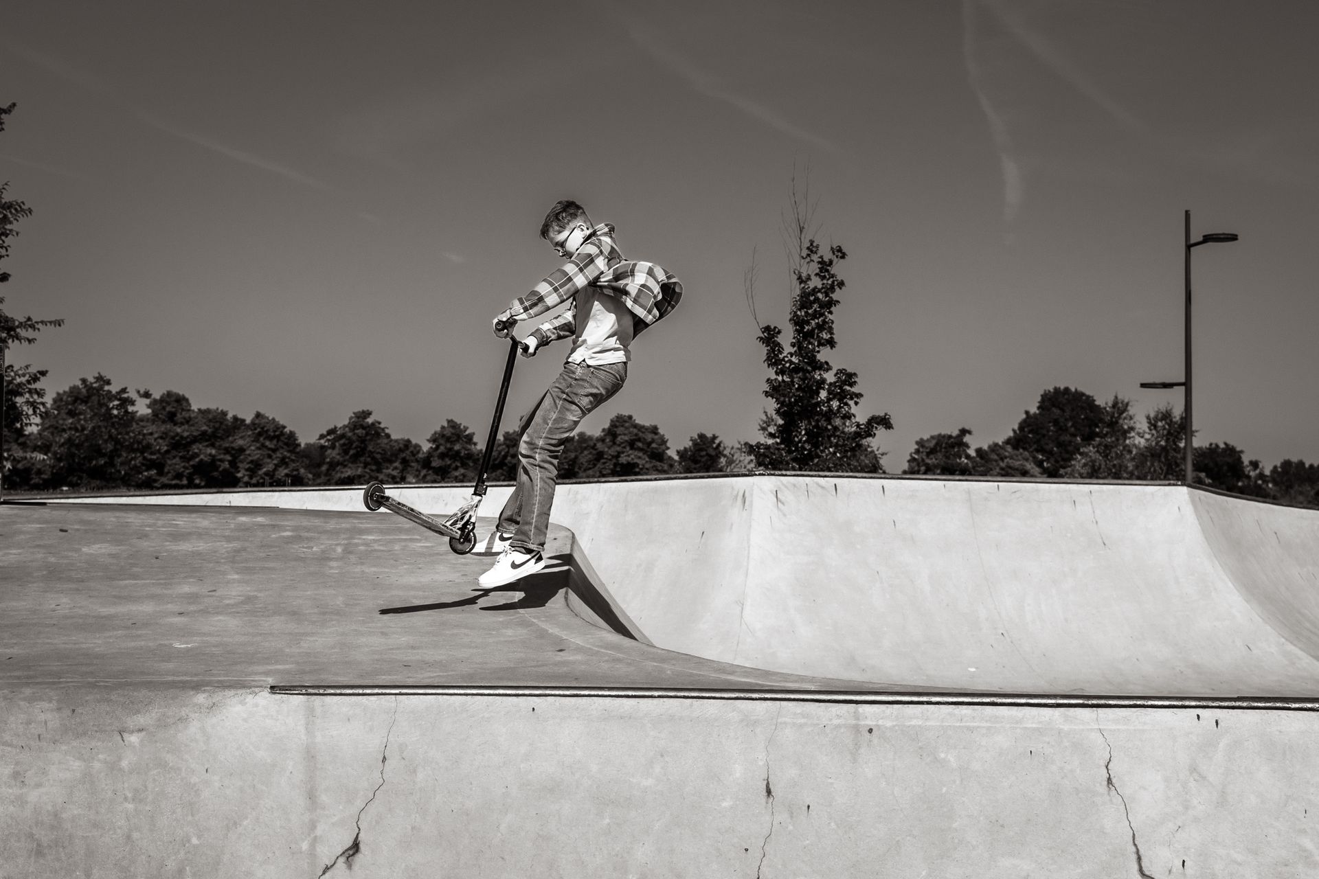Een persoon doet een trucje op een scooter in een skatepark.