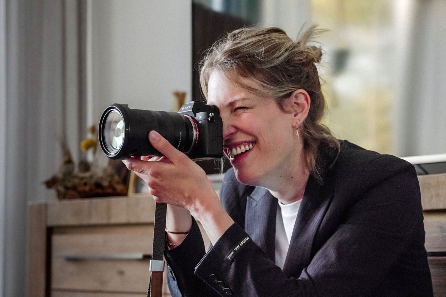 Een vrouw lacht terwijl ze een foto maakt met een camera.