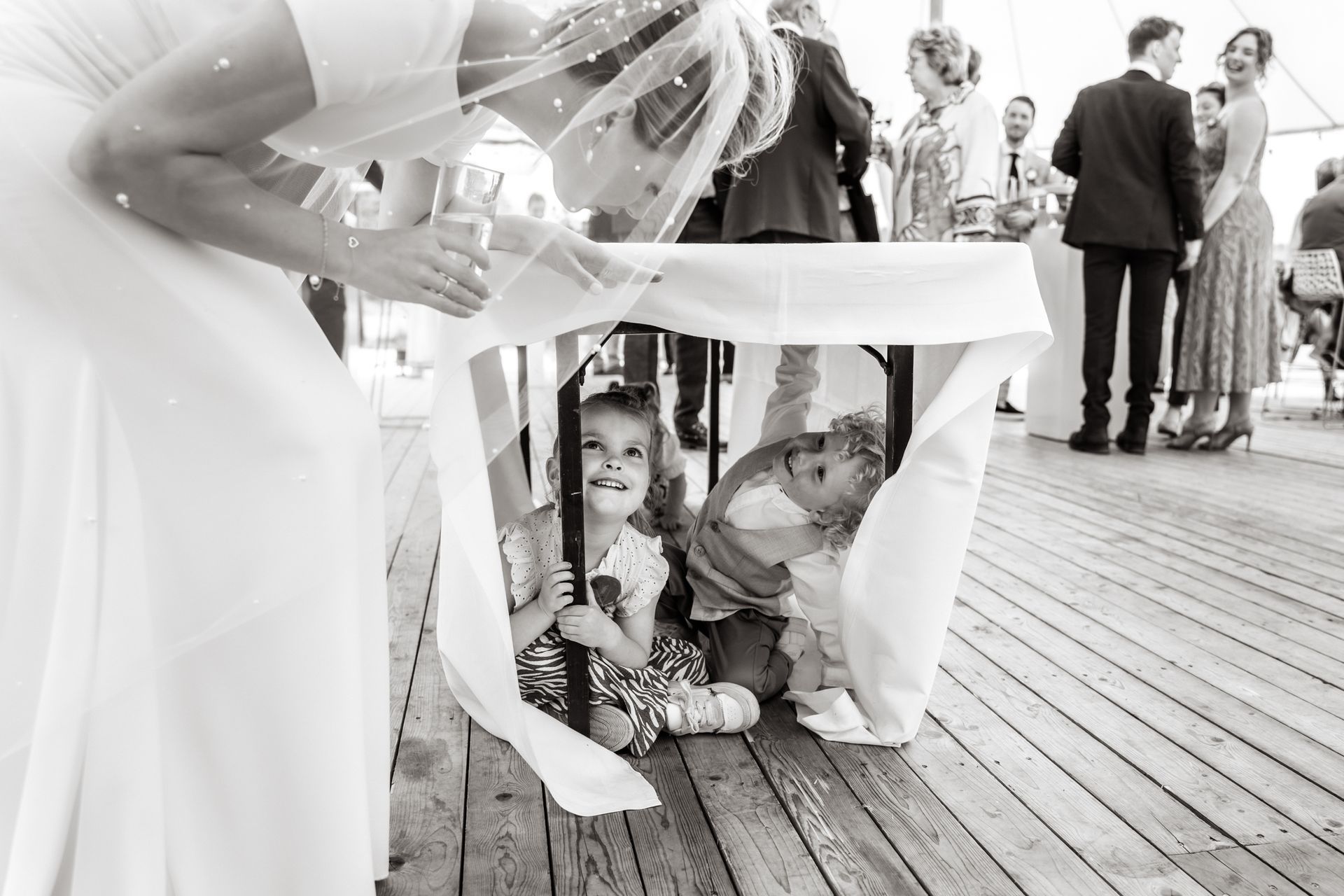 Een bruid en bruidegom spelen met hun kinderen op een huwelijksreceptie.