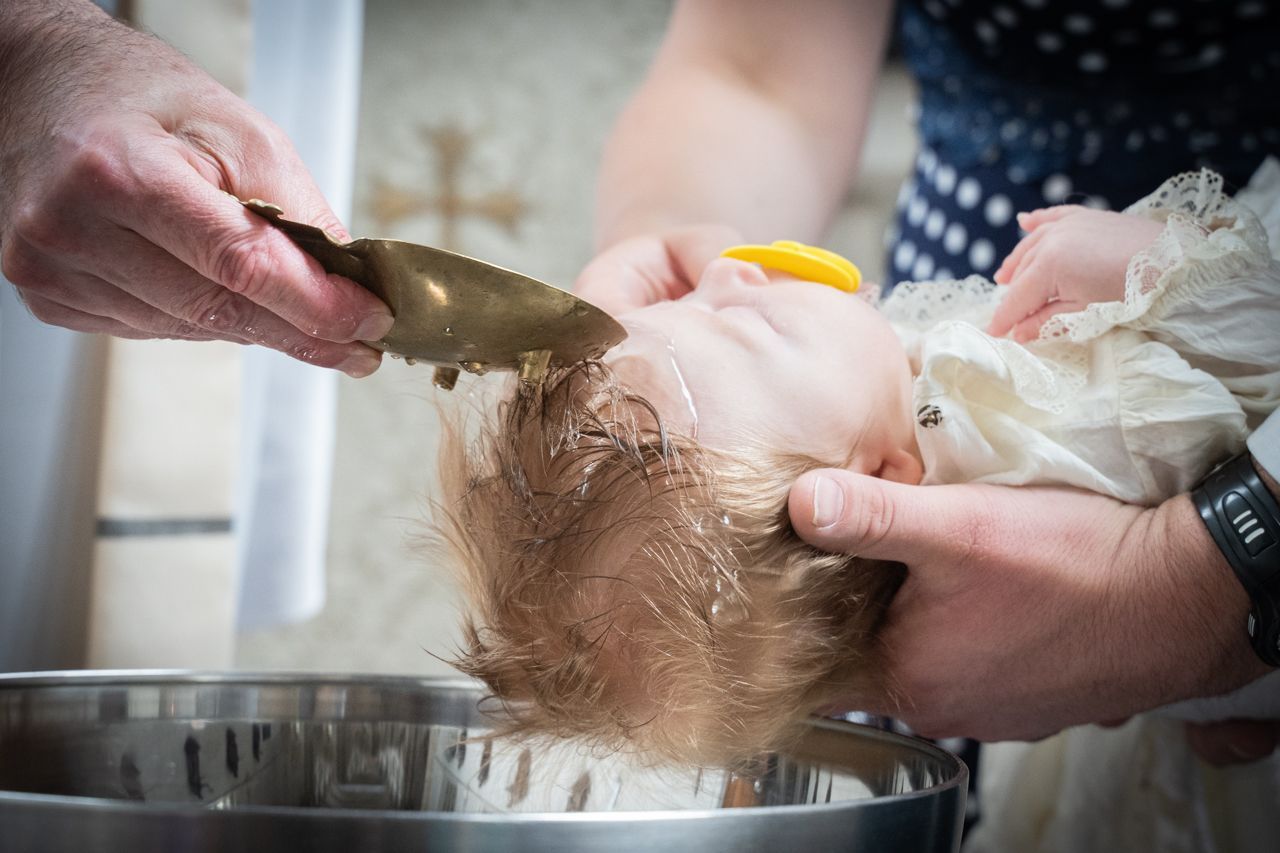 Een baby wordt gedoopt.