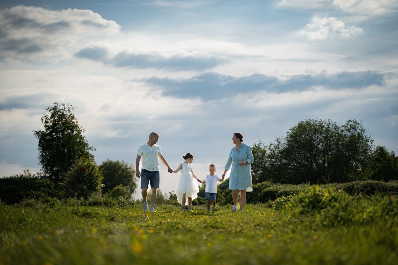 Een gezin loopt hand in hand door een grasveld.