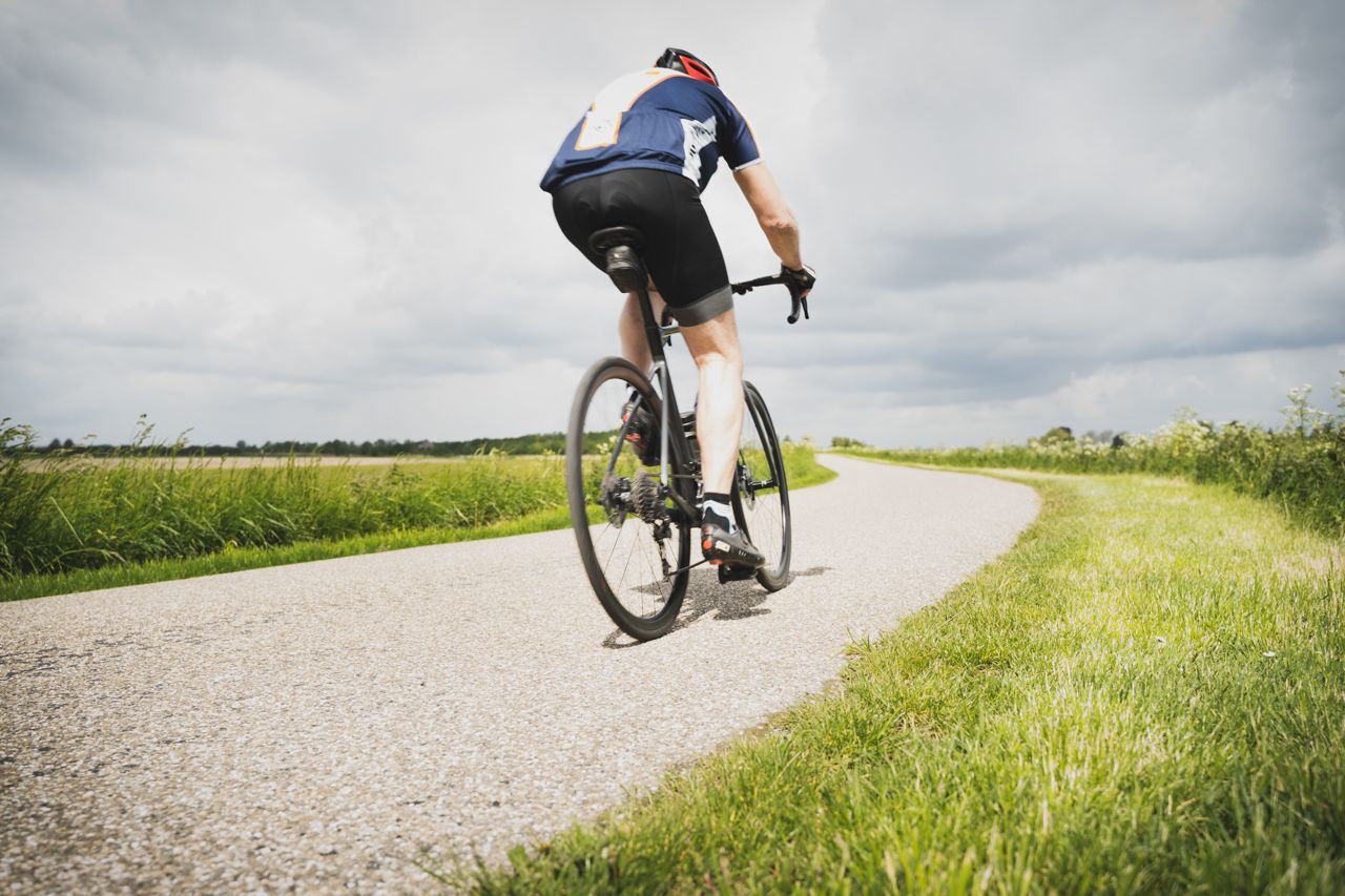 Een man fietst over een onverharde weg.