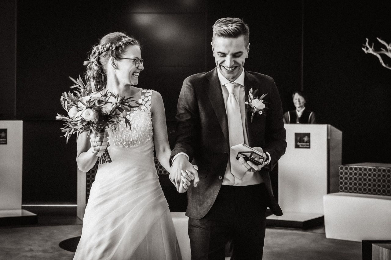 Een zwart-witfoto van een bruid en bruidegom die elkaars hand vasthouden