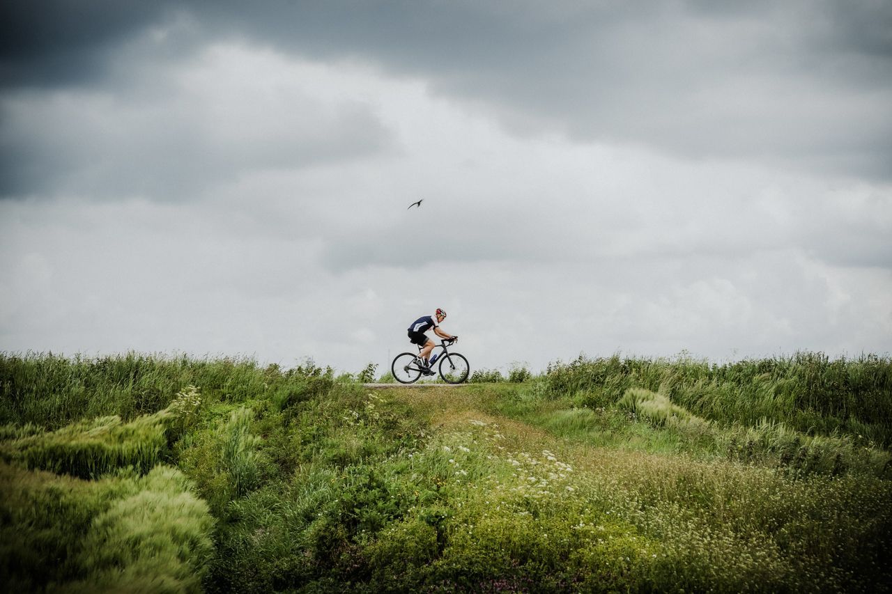 Een man fietst bovenop een met gras begroeide heuvel.