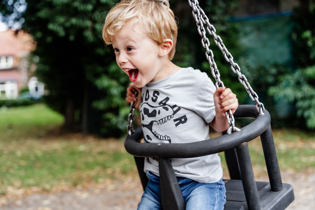 Een jonge jongen zit op een schommel in een park.