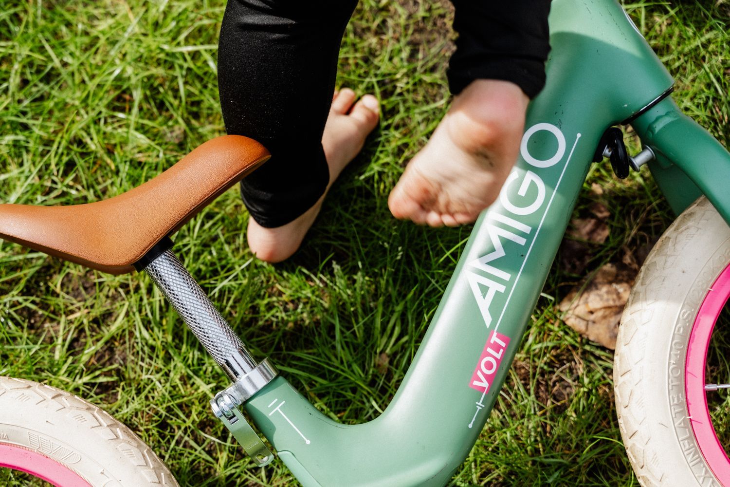Een persoon rijdt op een groene amigofiets in het gras.
