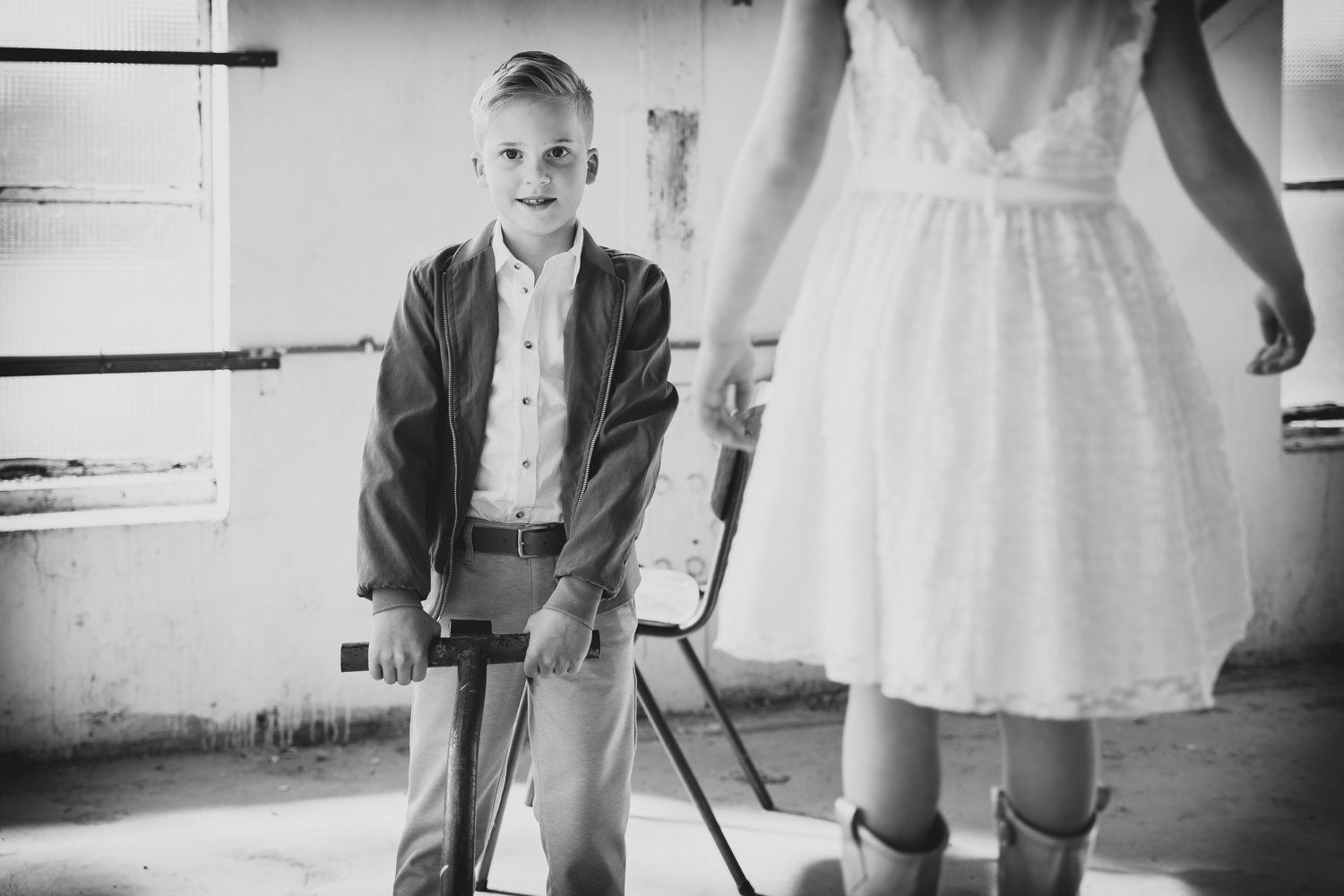 Een jongen trekt een kan met een meisje erop in een witte jurk.