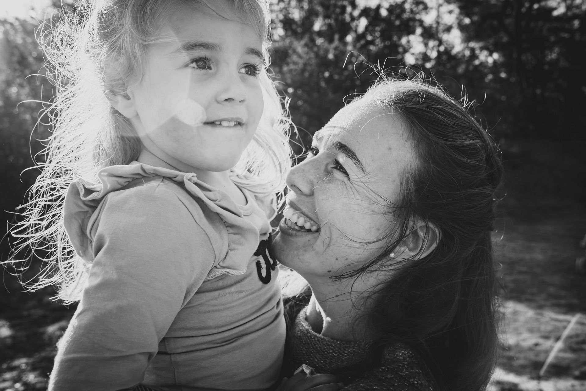 Op een zwart-witfoto houdt een vrouw een klein meisje in haar armen.