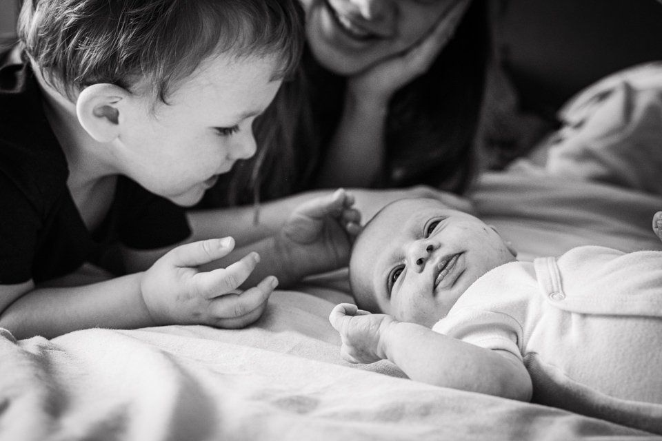 Een zwart-witfoto van een jongetje dat naar een baby kijkt.