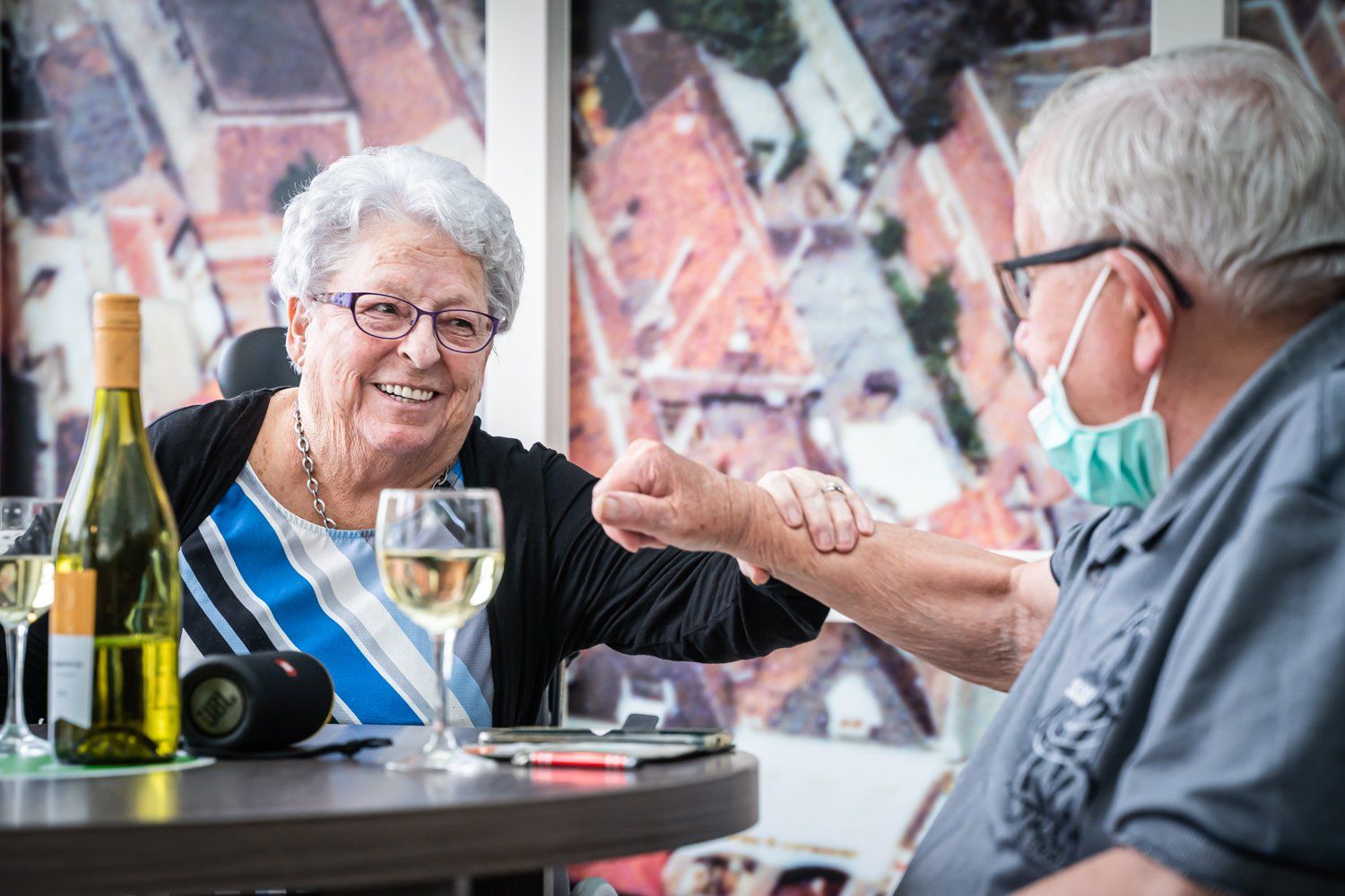 Een man en een vrouw zitten aan een tafel met wijnglazen en een fles wijn.