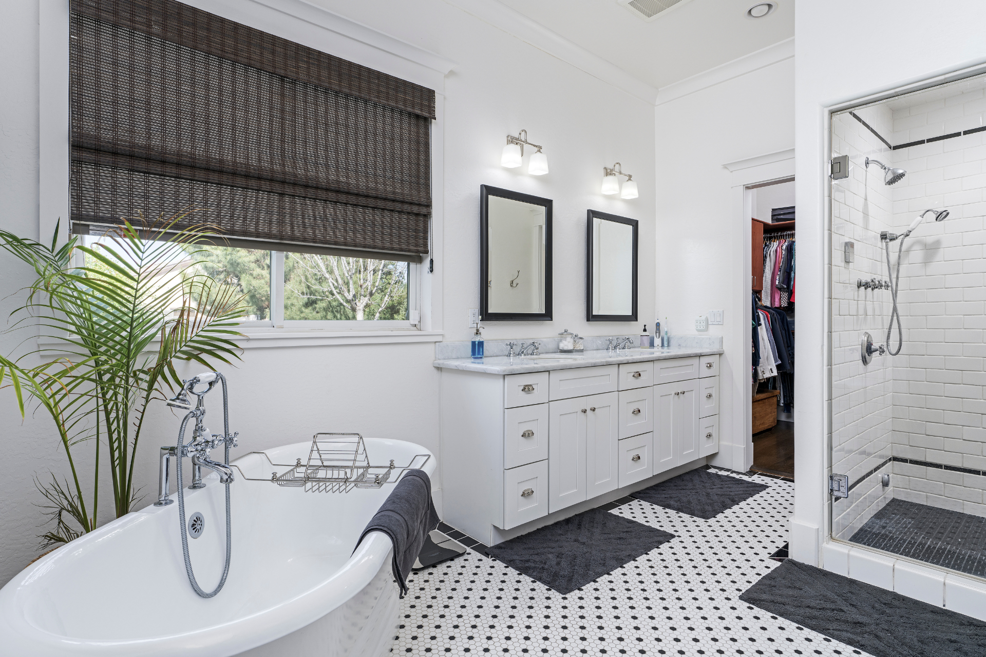 A bathroom with a tub , sink , mirrors and a walk in shower.