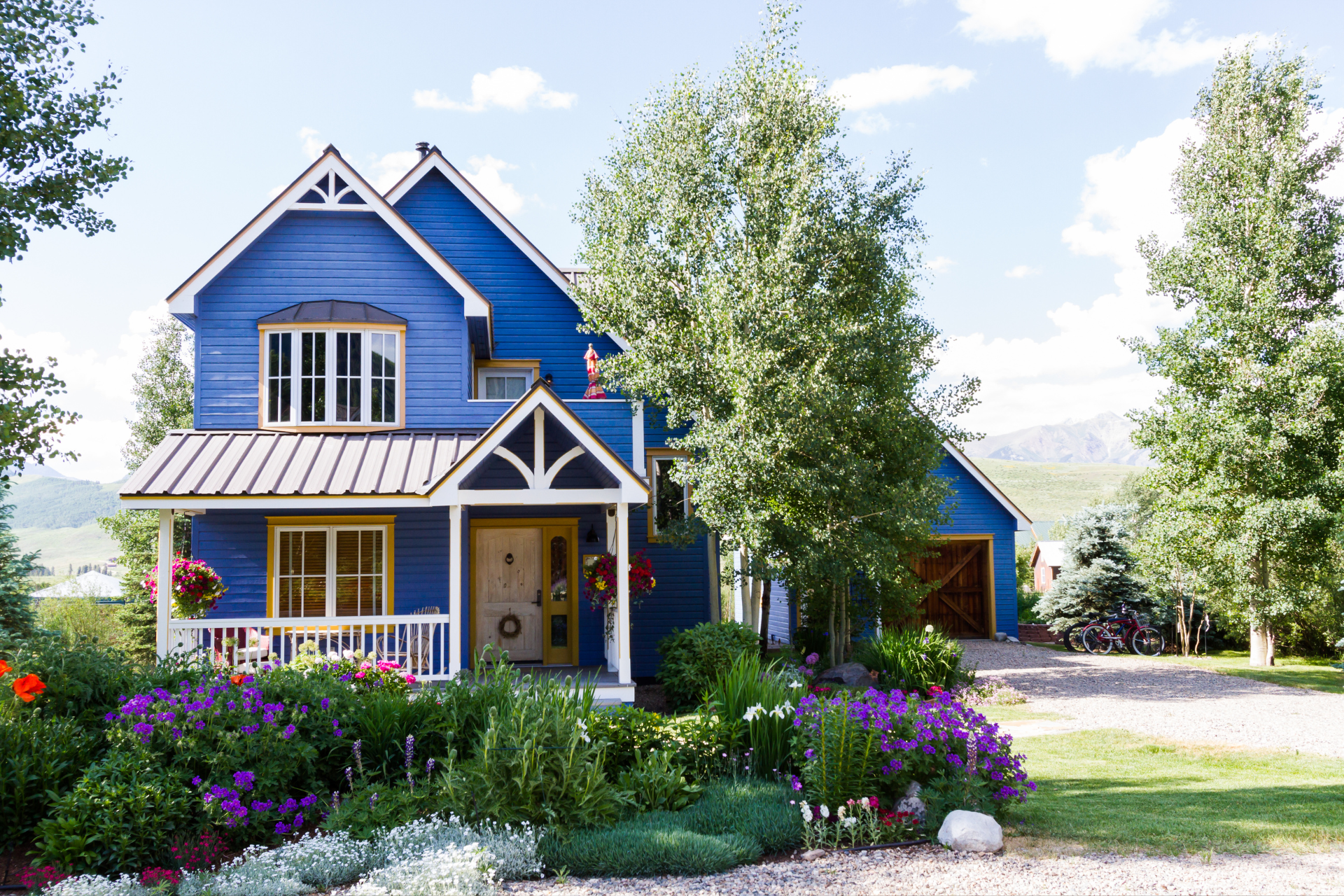 A blue house with purple flowers in front of it