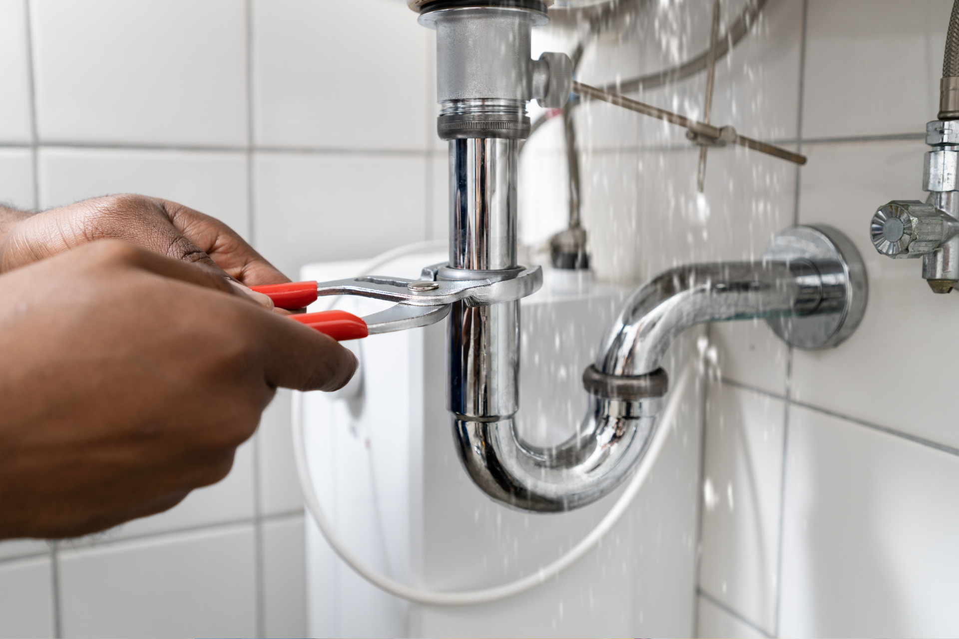 A person is fixing a bathroom sink with a wrench.
