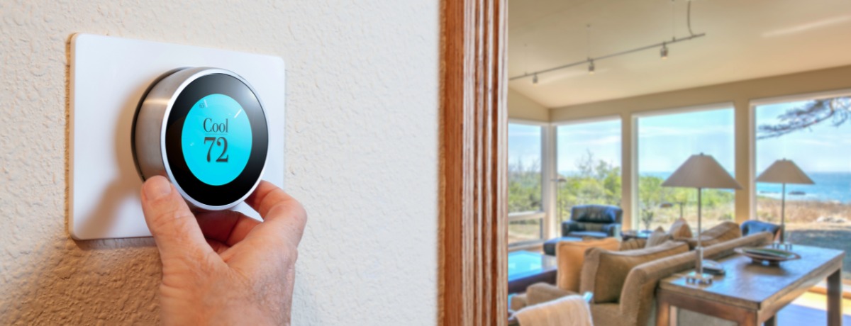 A person is adjusting a thermostat in a living room.
